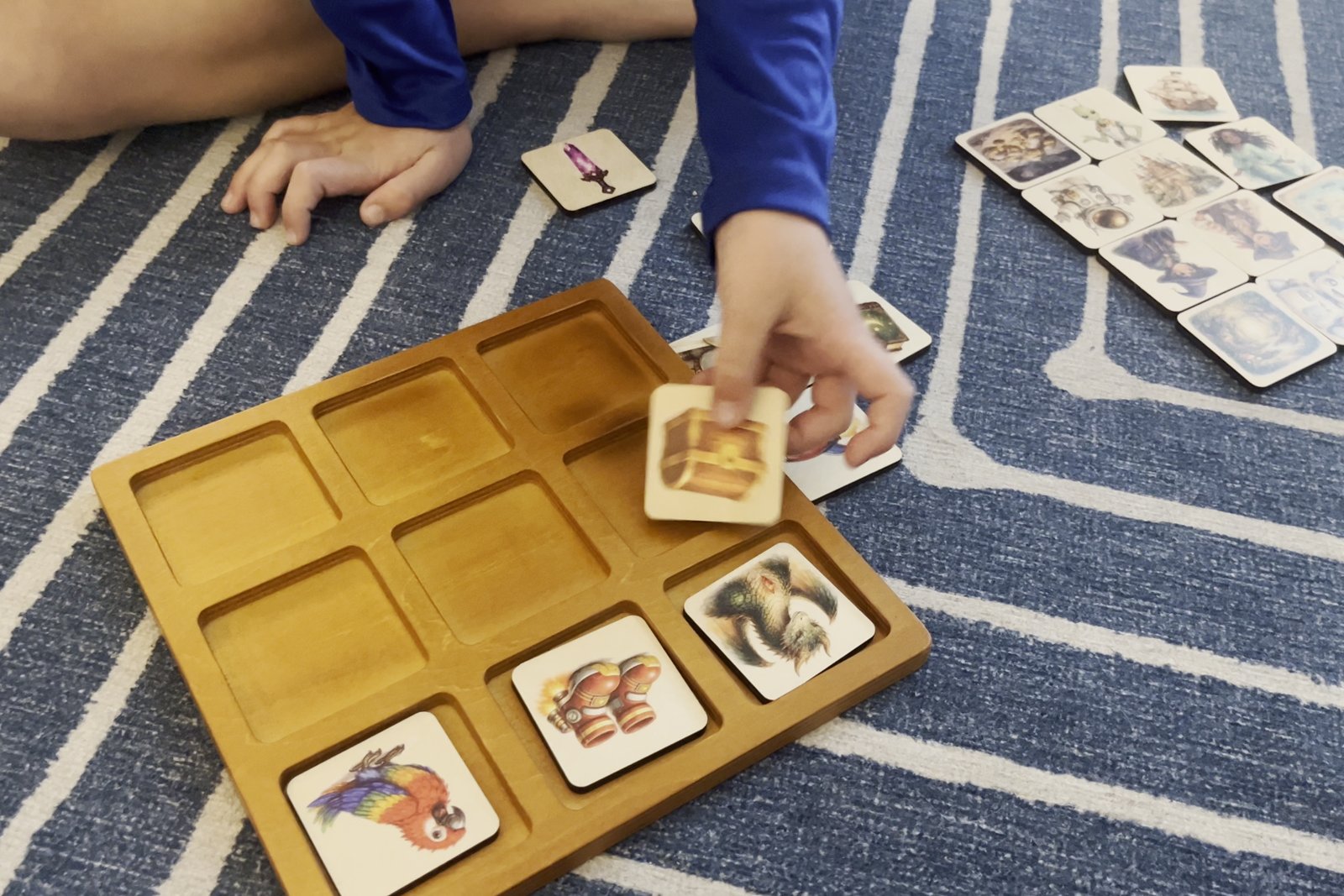 Small hands laying wooden story tiles on the tray